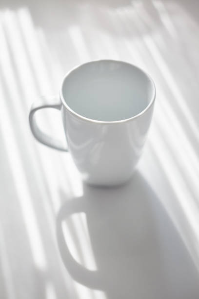 istock Back lit white mug on office table in the morning 1055073234