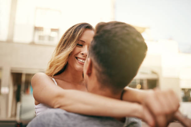 Affectionate young couple hugging and looking into each other's eyes while standing together in the city