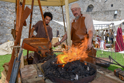 Bellinzona, Switzerland - 27 May 2018: Blacksmith who is forging a sword at the medieval market on Castelgrande castle at Bellinzona on the Swiss alps