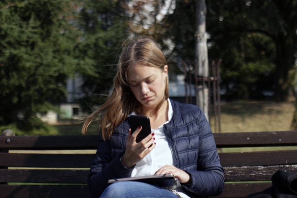 istock Young woman using her mobile phone in the public park 1055081520