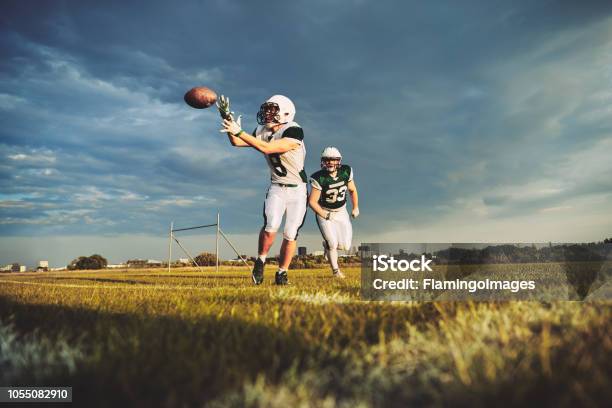 American Football Player Catching A Pass During Team Drills Stock Photo - Download Image Now