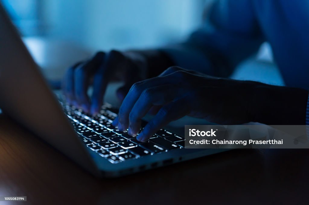 close up programmer man hand typing on keyboard laptop for register data system or access password at dark operation room , cyber security concept Computer Crime Stock Photo