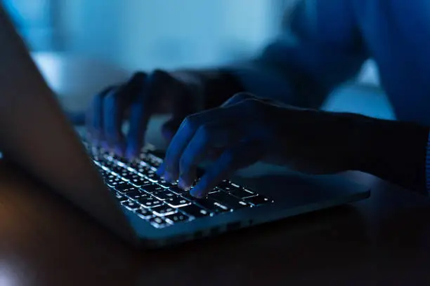 Photo of close up programmer man hand typing on keyboard laptop for register data system or access password at dark operation room , cyber security concept