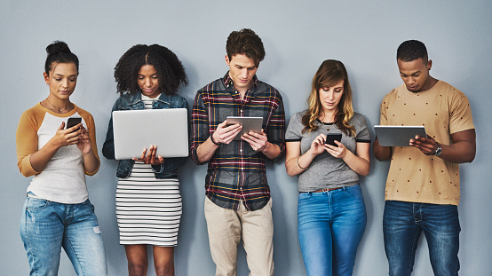 Studio shot of a group of young people using wireless technology against a gray background