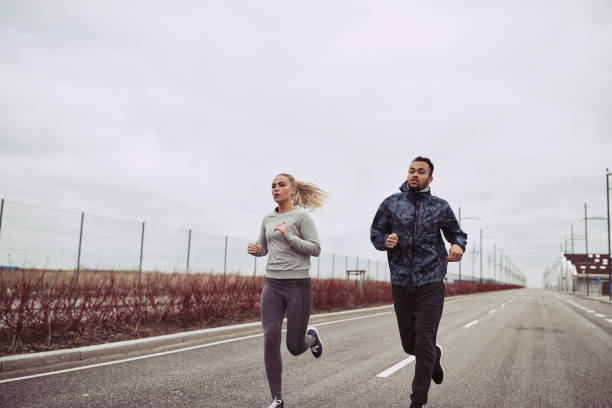 istock Diverse young couple running along a country road 1055090446