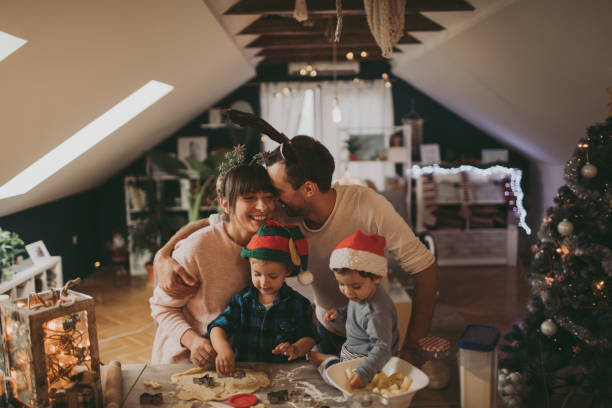 Baking Christmas cookies with my family Photo of a cute young family baking Christmas cookies during Christmas holidays, all dressed up as Santa, an Elf and Rudolph the Reindeer Christmas Tree Cookie stock pictures, royalty-free photos & images