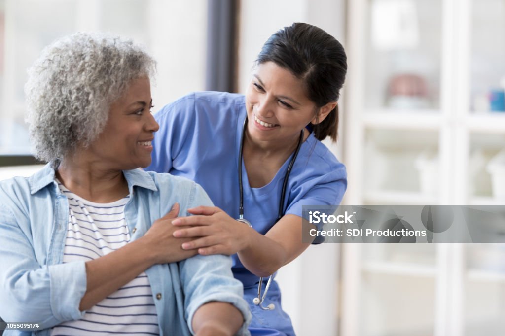 Nurse with senior patient Caring nurse smiles at an African American senior female patient. Patient Stock Photo