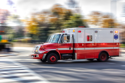 Photo of an red ambulance at a city street. Blurred motion. Urgency. Emergency