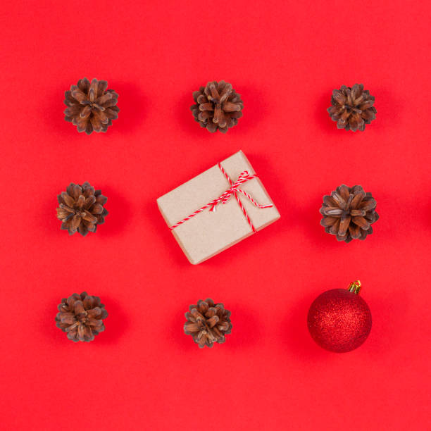 istock Christmas composition. Pattern made of pine cones, christmas decoration and gift box on red background. Top view, flat lay 1055098698