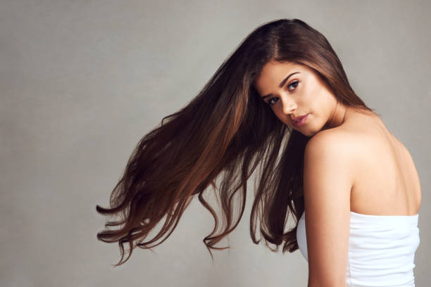 She's not sharing her hair secrets Studio shot of a young beautiful woman with long gorgeous hair posing against a grey background strapless stock pictures, royalty-free photos & images