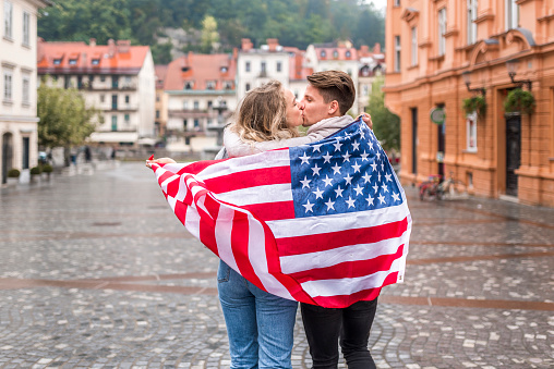 Young cheerful couple with American flag in the city.