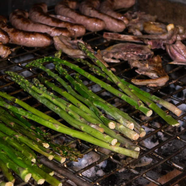 Summer grill preparation process. Sausages, lamb meat and asparagus grilled on the griddle. Summer grill preparation process. Sausages, lamb meat and asparagus grilled on the griddle. asparagus organic dinner close to stock pictures, royalty-free photos & images