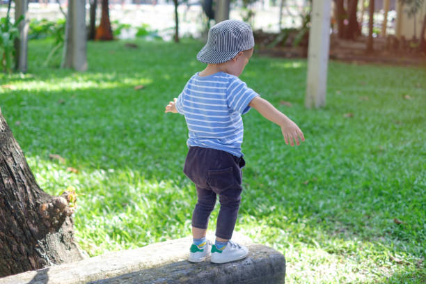 linda asiática 18 meses/1 año viejo niño bebé niño niño caminar sobre barra de equilibrio en el parque - barra de equilibrio fotografías e imágenes de stock