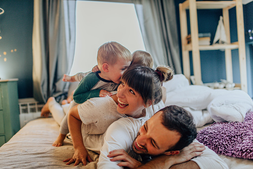 Photo of a young family enjoying their time together in family bedroom on Sunday morning