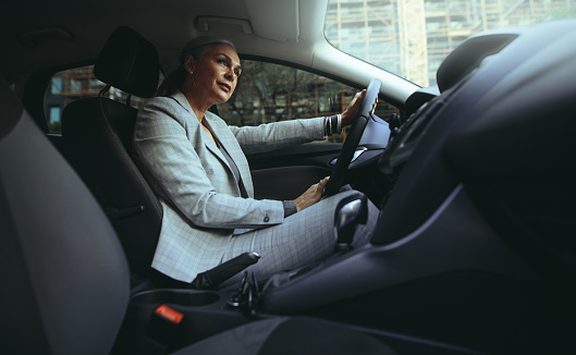 Mature woman driving a car. Senior female driver at a wheel of a modern car.