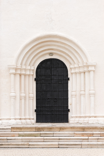 The big black door is the gate to the white building. Architectural details of the past