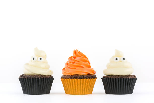 Festive close-up view of decorative homemade halloween white and orange frosted cupcakes with eyes on white background. Text space concept. Festive close-up view of decorative homemade halloween white and orange frosted cupcakes with eyes on white background. Text space concept. halloween cupcake stock pictures, royalty-free photos & images