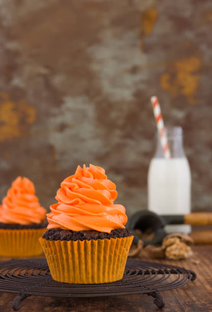 istock Halloween homemade cupcakes with milk bottle at rusty orange background. Space for text. 1055128236