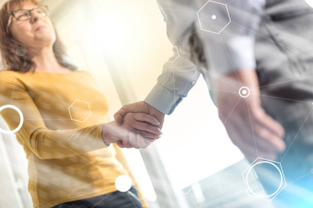 istock Woman and man shaking hands in office, light effect 1055128338