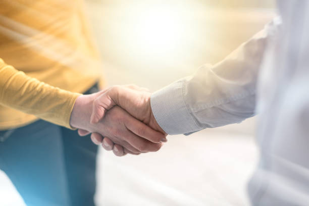 istock Woman and man shaking hands in office, light effect 1055130924