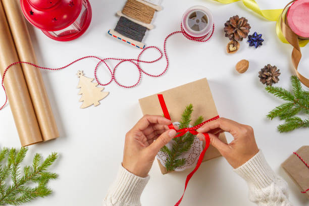 istock Christmas gift wrapping. Woman's hands packing Christmas presents on white table 1055132678