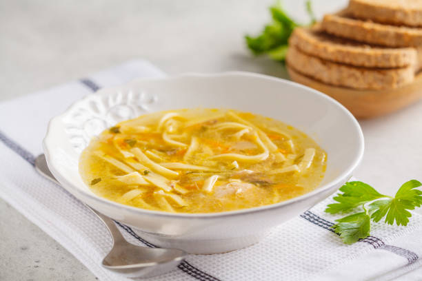 istock Homemade chicken noodle soup in a white plate, white background. 1055134860