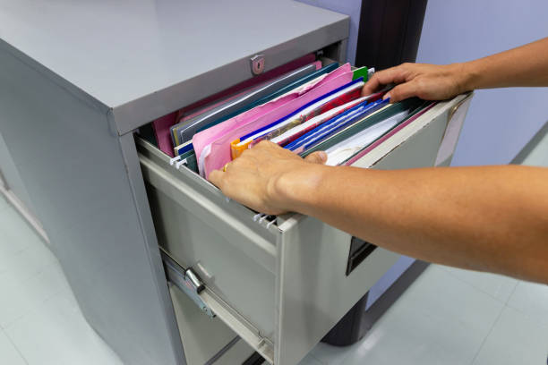 istock Hand of Man Search files document in a file cabinet in work office 1055135010