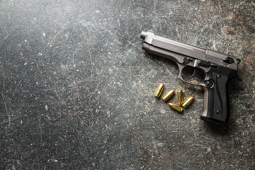 9mm pistol bullets and handgun on black table.