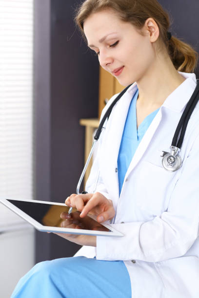 istock Woman doctor using white tablet computer while working in hospital 1055146294