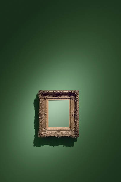 Golden empty antique picture frame hanging on green wall