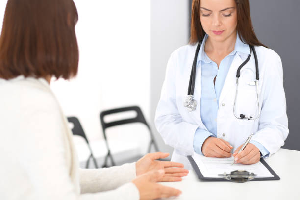 istock Doctor and  patient  discussing something while standing near reception desk in emergency hospital. Physician at work in clinic. Medicine and health care concept 1055155044
