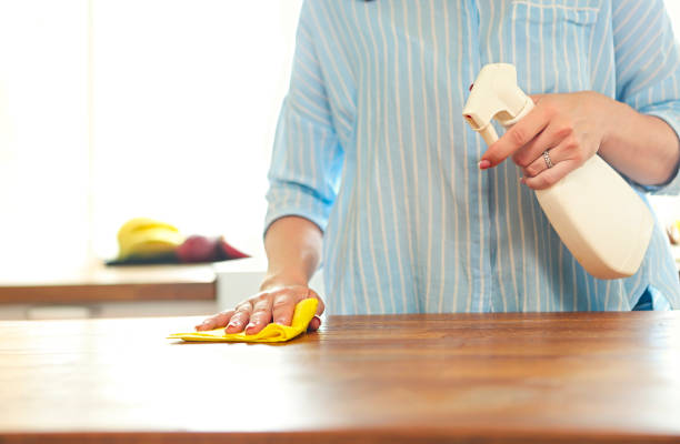 Conceptual image of kitchen cleaning. Close up of human handholding spray bottle with cleaning liquid Conceptual image of kitchen cleaning. Close up of human handholding spray bottle with cleaning liquid. Clean kitchen countertop and stove in background spray bottle stock pictures, royalty-free photos & images