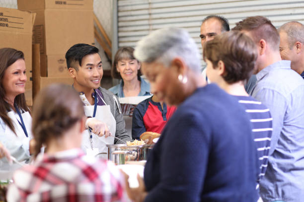 istock Multi-ethnic group of volunteers serves food at soup kitchen. 1055189410