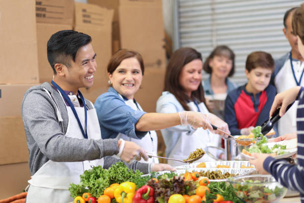 istock Multi-ethnic group of volunteers serves food at soup kitchen. 1055190192