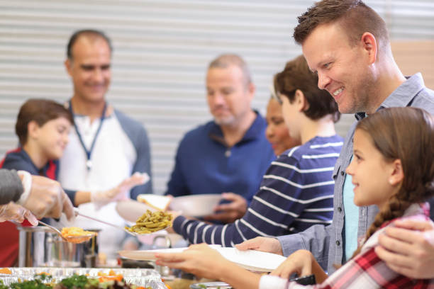 istock Multi-ethnic group of volunteers serves food at soup kitchen. 1055190752