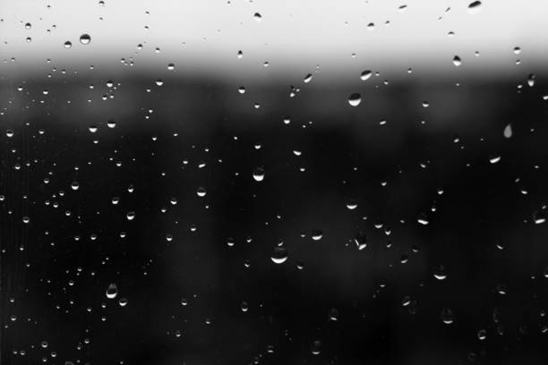 istock Rain drops on window with blured background in black and white. 1055192518