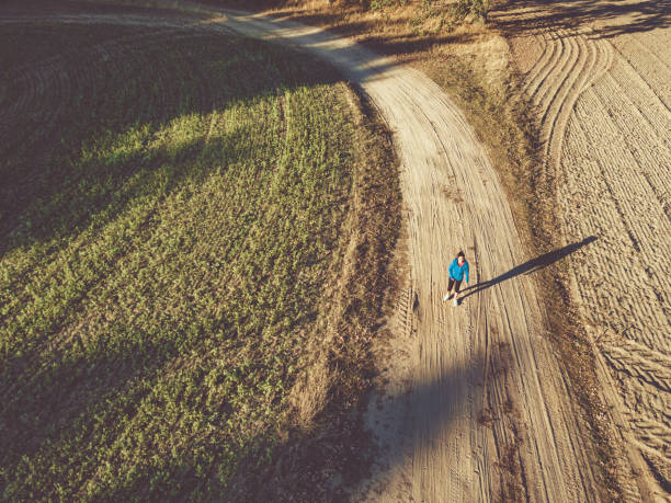istock drone view on single woman running on country road 1055197054