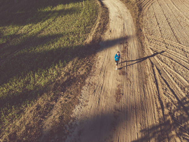 istock drone view on single woman running on country road 1055197210