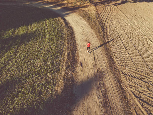 istock drone view on single woman running on field 1055197282