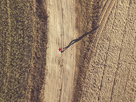 drone view on woman running on autumn field at late afternoon