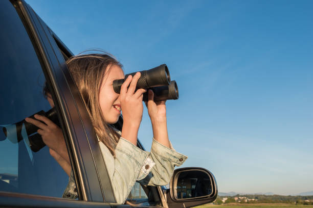 istock Cheerful Girl Looking Through Binoculars While Traveling in the Car 1055198450