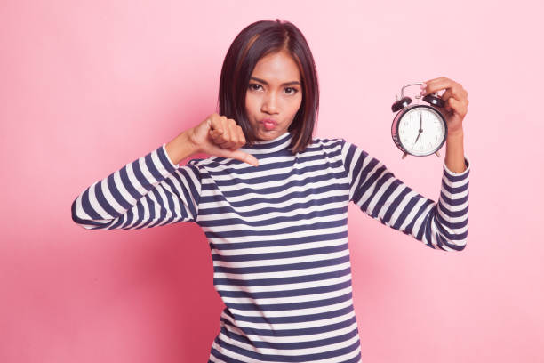 istock Young Asian woman thumbs down with a clock. 1055202496