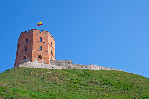 Vilnius / Lithuania - September 2 2018:Gediminas' Tower or Castle, the remaining part of the Upper Castle in Vilnius, Lithuania with lithuanian flag waving on a green hill and blue sky
