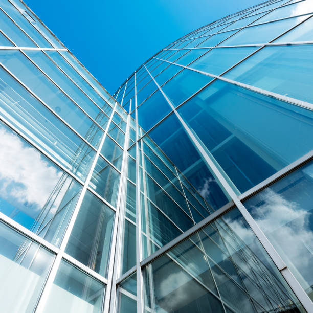 istock modern blue glass and metal office facade reflects clouds and blue sky 1055210046