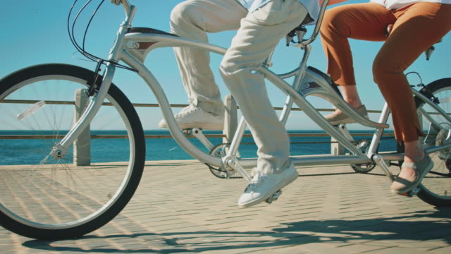 Senior couple riding tandem bicycle on promenade