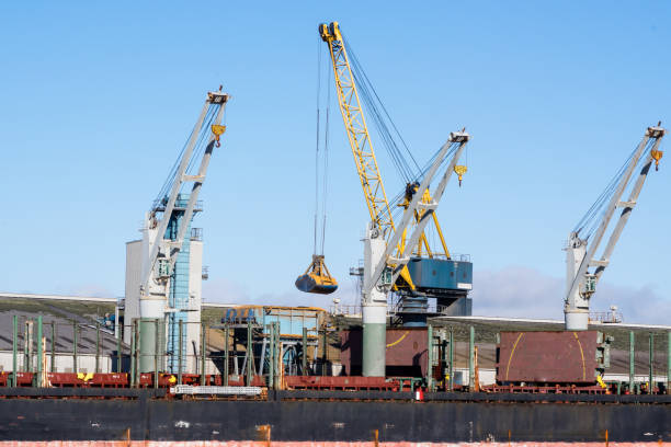 Cranes unloading bulk grain from a ship at the wharf and concrete storage silos at Belfast Harbour, Northern Ireland.  Belfast Harbour is Northern Ireland's principal maritime gateway and logistics hub, serving the Northern Ireland economy and increasingly that of the Republic of Ireland. Around 70% of Northern Ireland's and 20% of the entire island's seabourne trade is handled at the Harbour each year.