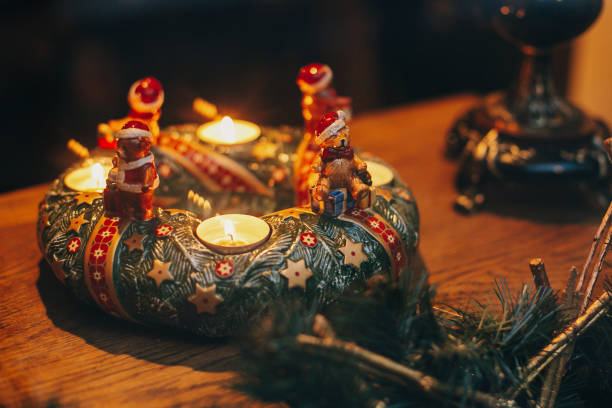 vintage wieniec bożonarodzeniowy ze świecami i zabawki niedźwiedzie na drewnianym stole na europejskiej ulicy miasta. świąteczne dekoracje i oświetlenie w ferie zimowe w mieście. - poinsettia christmas candle table zdjęcia i obrazy z banku zdjęć