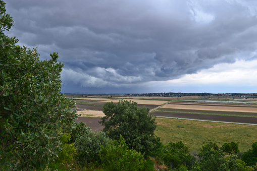 The view of storm clouds from the ruins of Troy across the plain of Ilium to the Aegean Sea.