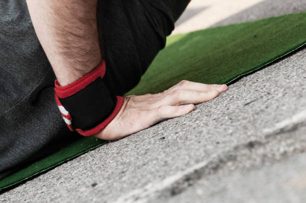 Closeup of a male hand with wrist band doing push ups on green mat Closeup side view of a mans right hand with wrist band doing push ups on green mat burpee stock pictures, royalty-free photos & images