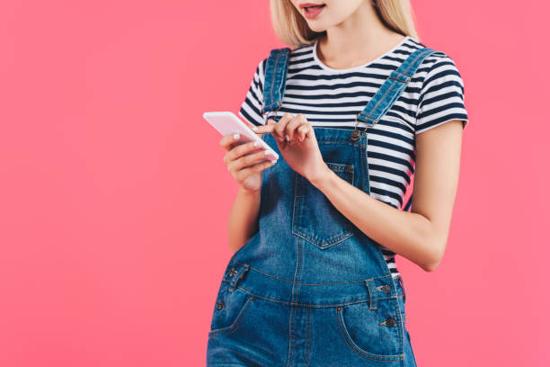 istock partial view of woman using smartphone isolated on pink 1055222360